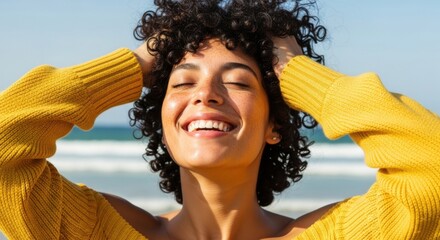 Smiling woman enjoying the sun and sea at a beautiful beach in bright yellow sweater