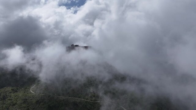 Ruins of Citadelle Laferriere, fortress on mountaintop shrouded in clouds, Cap-Ha&iuml;tien, Haiti. Aerial forward