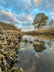 River scene reflecting cloudy sky and autumnal trees
