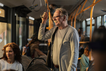 Senior man commuting on public bus, holding handrail
