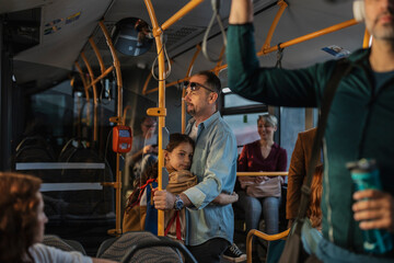 Father daughter commuting by public transport standing in urban bus