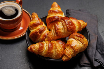 Aromatic croissants in bowl with cup of coffee