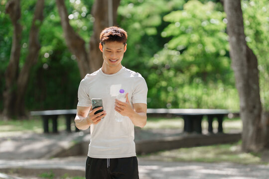 Young asian man checking phone during exercise break - Powered by Adobe