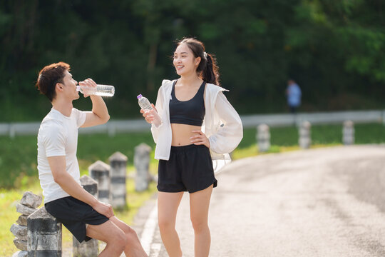 Young couple resting drinking water after exercising