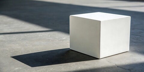 A white cube casting a shadow on a concrete surface.