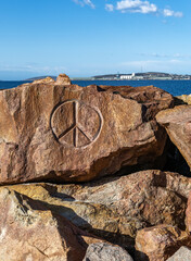 A granite rock with an engraved peace sign.
The breakwater at Bandy Creek fishing boat harbor, with the port of Esperance in the background.
