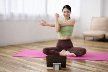 Tablet-Focused Shot of Middle-Aged Japanese Woman Taking Online Yoga Class at Home