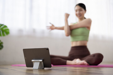 Tablet-Focused Shot of Middle-Aged Japanese Woman Taking Online Yoga Class at Home