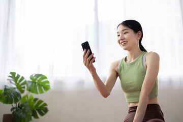 Smiling Woman in Activewear Using Smartphone at Home
