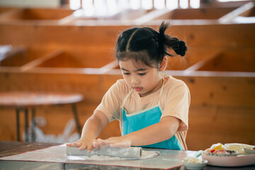 Young Girl Engaging in Creative Play While Rolling Dough at a Wooden Table in a Cozy Kitchen Setting
