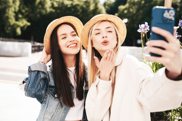 Two young beautiful smiling hipster female in trendy summer clothes. Carefree women posing in the...