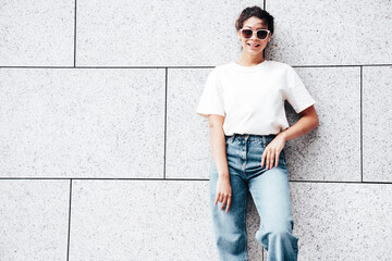 Young beautiful smiling hipster woman in trendy summer white t-shirt and jeans clothes. Carefree...