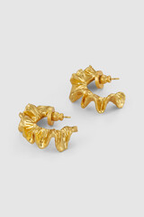 Pair of golden hoop earrings with textured surface on a plain background