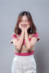 Smiling Asian Woman with Eyes Closed and Hands on Face