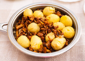 appetizing fried chanterelle mushrooms with new potatoes in skillet