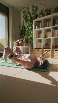 Senior woman doing chest press exercise with dumbbells on a mat at home
