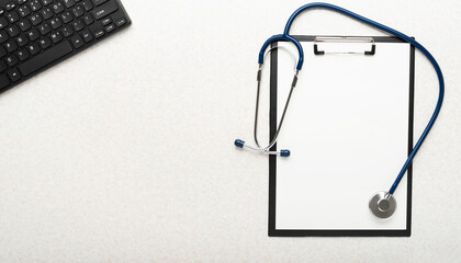 Medical background of stethoscope clipboard and computer keyboard flat lay on table with copy-space