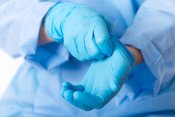 Healthcare professional putting on blue medical gloves on white background with copy space