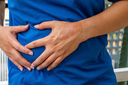 Man clutching abdomen in pain&mdash;possible liver-related symptoms such as hepatic inflammation, cirrhosis, or bile duct disorder. Liver disease, abdominal pain, hepatology.