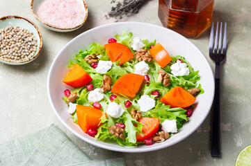 Salad with persimmon, feta cheese, pomegranate and nuts. Healthy eating. Vegetarian.