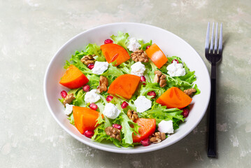 Salad with persimmon, feta cheese, pomegranate and nuts. Healthy eating. Vegetarian.