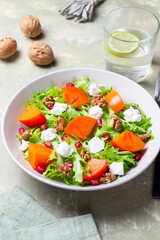 Salad with persimmon, feta cheese, pomegranate and nuts. Healthy eating. Vegetarian.