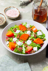 Salad with persimmon, feta cheese, pomegranate and nuts. Healthy eating. Vegetarian.