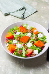 Salad with persimmon, feta cheese, pomegranate and nuts. Healthy eating. Vegetarian.