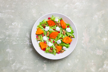 Salad with persimmon, feta cheese, pomegranate and nuts. Healthy eating. Vegetarian.