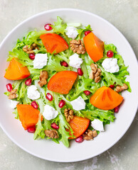 Salad with persimmon, feta cheese, pomegranate and nuts. Healthy eating. Vegetarian.