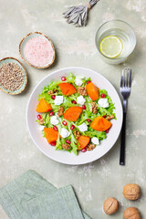 Salad with persimmon, feta cheese, pomegranate and nuts. Healthy eating. Vegetarian.