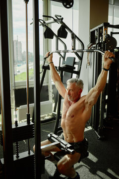 Middle Aged Man Exercising with Lat Pulldown Machine at Gym