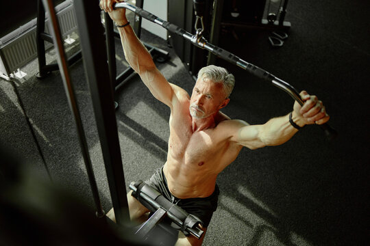 Middle Aged Man Exercising on Lat Pulldown Machine in Gym Setting