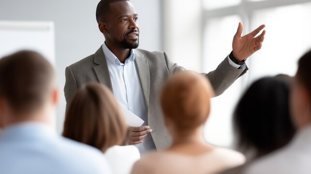 In a bright conference room, a skilled speaker passionately addresses a diverse audience, sharing insights on business strategies and professional growth during a recent training session