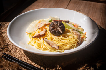 A rustic vegetarian noodle dish served with shiitake mushrooms, set amidst warm natural light, perfect for promoting vegan, Asian, food menus and healthy lifestyle concepts.