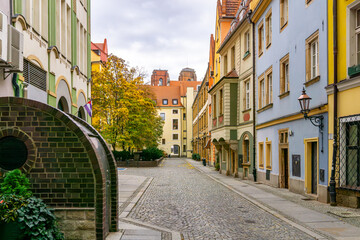 Fototapeta premium Garncarskie Passage in Wroclaw, colorful townhouses along cobblestone street, autumn trees, quiet historic urban pedestrian area in Old Town city center