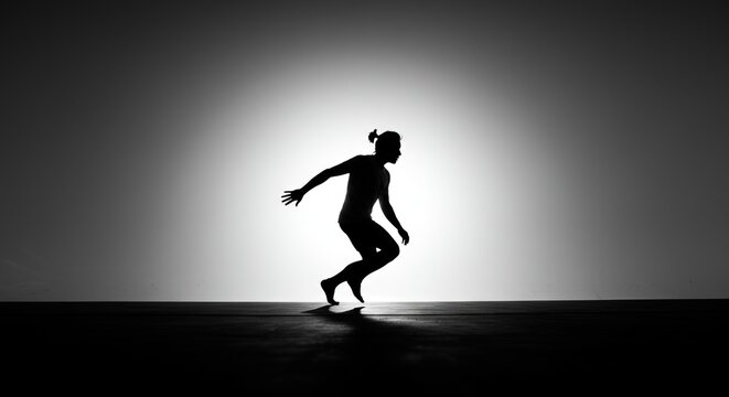 Dramatic silhouette of a modern dancer performing an energetic routine under a bright spotlight