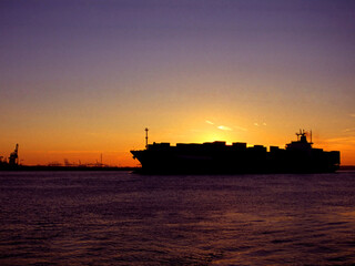 Silhouette of a cargo ship by sunset