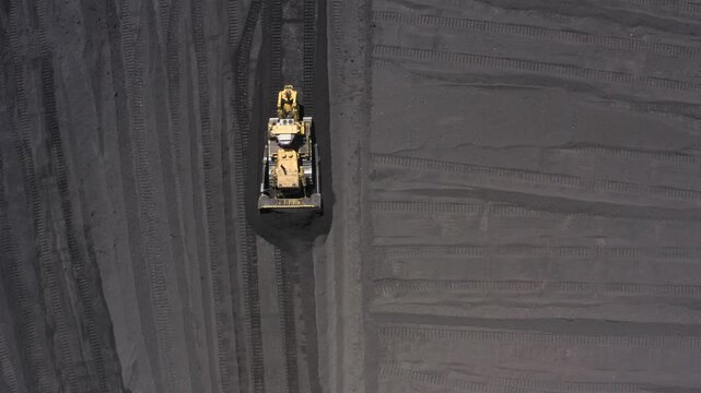 Aerial view of bulldozers directing coal at a thermal power plant for energy production