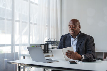 Mature businessman reading notebook planning strategy in office