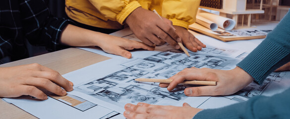 A vibrant scene depicting a collaborative design session where team members engage in planning an architectural project using blueprints and sketches, showcasing teamwork. SACTR