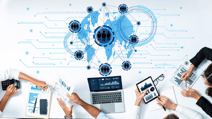 Team members engaged in a business meeting analyzing data with digital tools, emphasizing global...