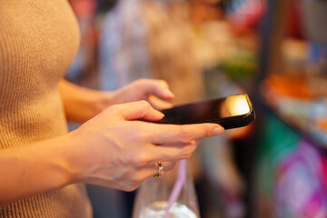 A woman uses her smartphone to make a mobile payment for street food at a lively outdoor festival.