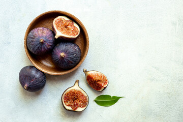 Fresh ripe figs on a wooden bowl top view on a stone background