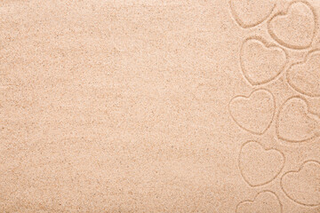 Heart shape prints on dry light brown sea sand background. Closeup. Love concept. Closeup. Empty place for text. Top down view.
