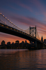 Fototapeta premium Steel arch bridge over river at sunset twilight with city skyline in the background 