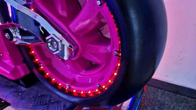 The plastic wheel of a racing motorcycle is a game simulator for children or part of a carousel. The LED light strip around the rim flashes and the music plays a pleasant song. chrome swingarm, car