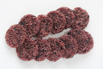 A bunch of uncooked Rengginang (or Ranginang), traditional Indonesian crackers made from raw glutinous black rice, laid out on a white surface before frying.