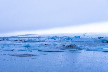Icebergs floating on glacial lagoon with cold winter landscape