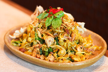 A vibrant plate of sayur urap, a traditional Indonesian mixed vegetable salad. Garnished with fresh herbs and served with crispy crackers (rempeyek).